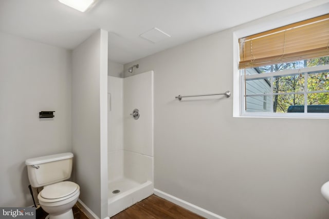 bathroom featuring toilet, a shower, and hardwood / wood-style floors