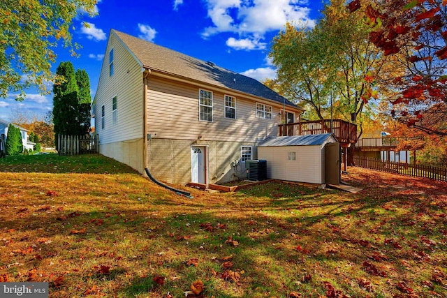 back of house with a wooden deck, a shed, a lawn, and central AC