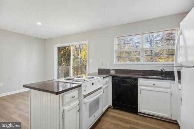 kitchen with white appliances, white cabinets, plenty of natural light, sink, and kitchen peninsula