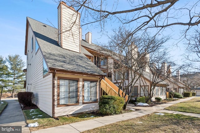 view of side of home featuring roof with shingles and a chimney