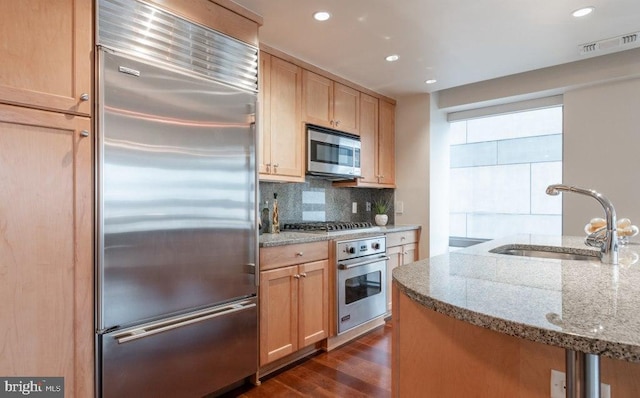 kitchen with sink, dark wood-type flooring, stainless steel appliances, tasteful backsplash, and light brown cabinetry