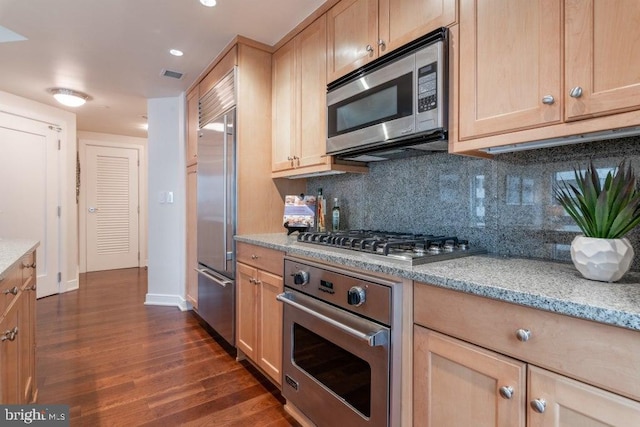 kitchen with stainless steel appliances, light brown cabinets, light stone counters, and decorative backsplash