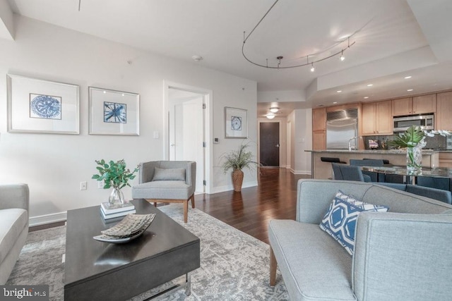 living room with dark hardwood / wood-style flooring and rail lighting