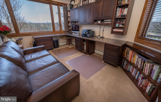 carpeted home office featuring a baseboard radiator, plenty of natural light, and built in desk