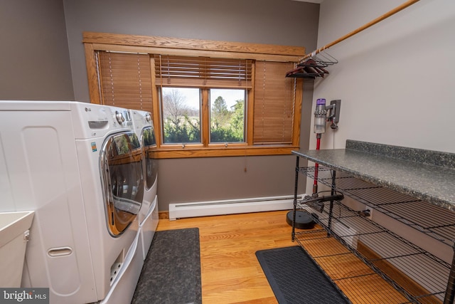 laundry area with wood-type flooring, a baseboard heating unit, and washer and clothes dryer