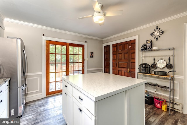 kitchen featuring a center island, white cabinetry, dark hardwood / wood-style flooring, stainless steel fridge, and crown molding