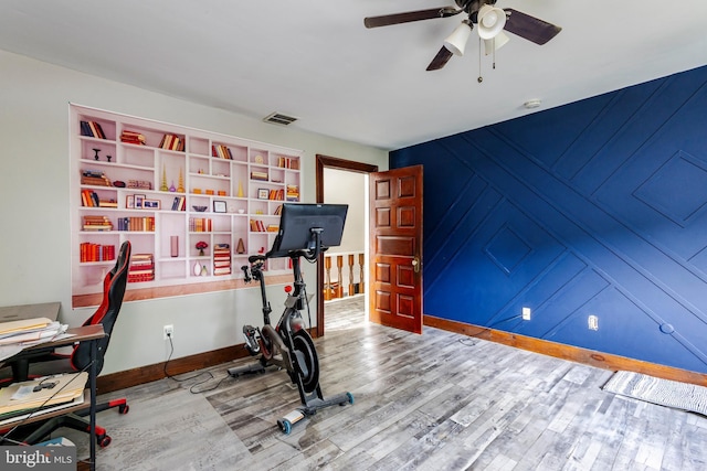 workout area with built in features, hardwood / wood-style flooring, and ceiling fan