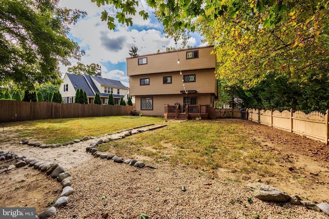 back of property featuring a wooden deck and a yard