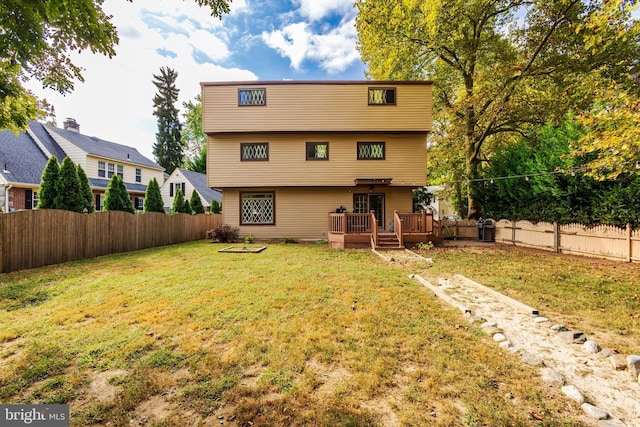 back of property with a deck and a yard