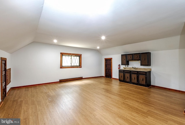 unfurnished living room featuring sink, light wood-type flooring, vaulted ceiling, and baseboard heating