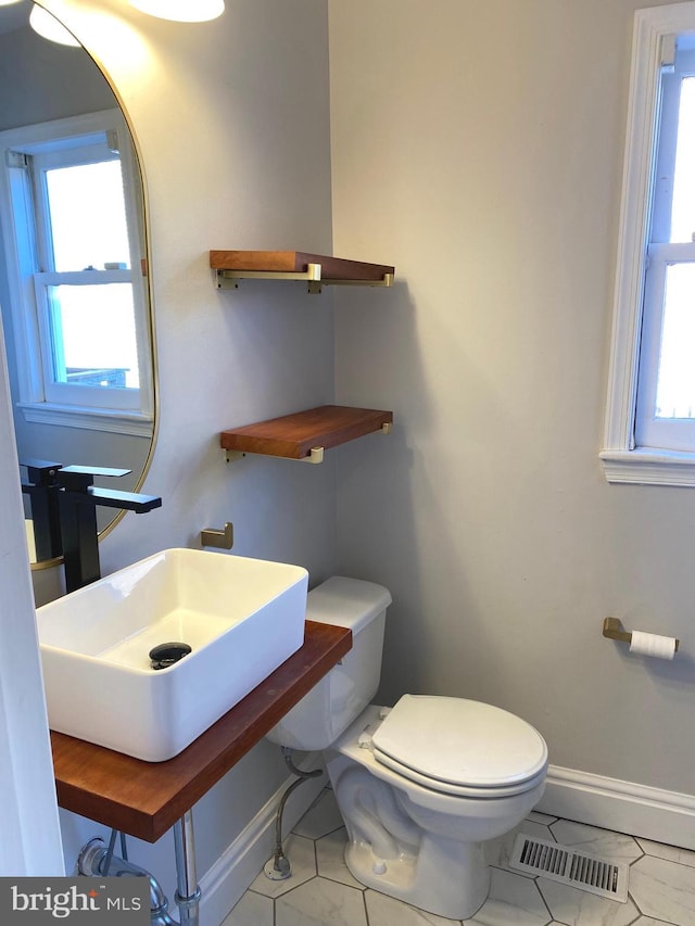 bathroom featuring sink, toilet, plenty of natural light, and tile patterned flooring