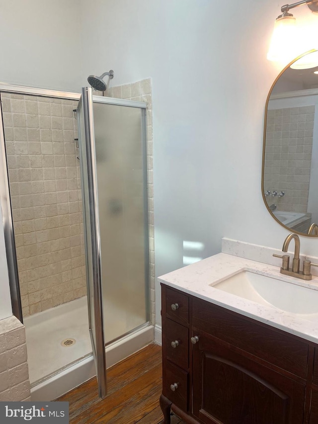 bathroom with hardwood / wood-style floors, a shower with door, and vanity