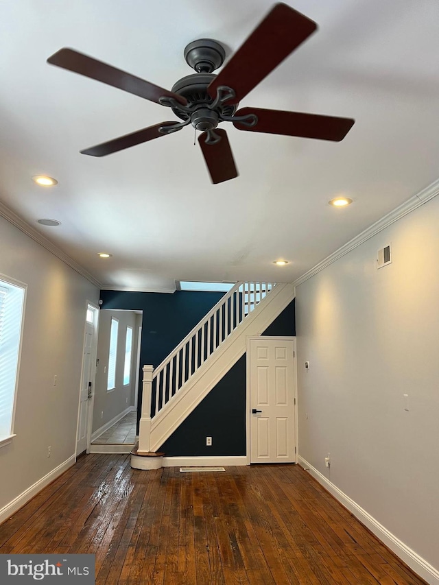 unfurnished living room featuring ceiling fan, dark hardwood / wood-style flooring, ornamental molding, and a healthy amount of sunlight