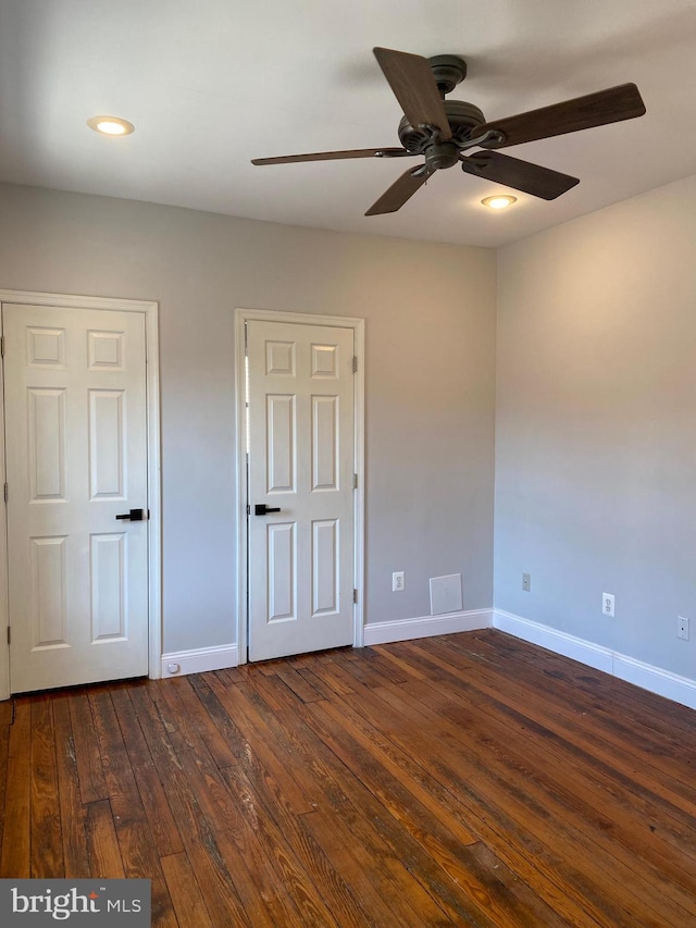 unfurnished bedroom with ceiling fan and dark wood-type flooring