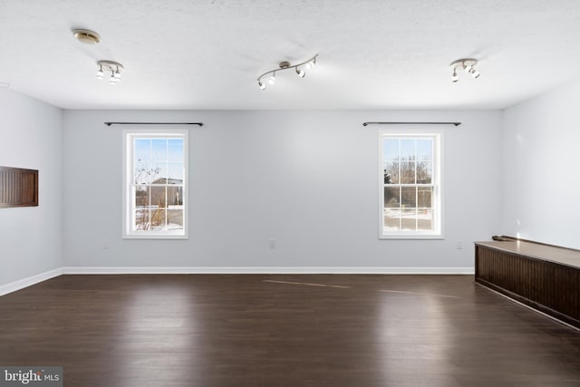 unfurnished room featuring dark hardwood / wood-style flooring, a textured ceiling, and a wealth of natural light