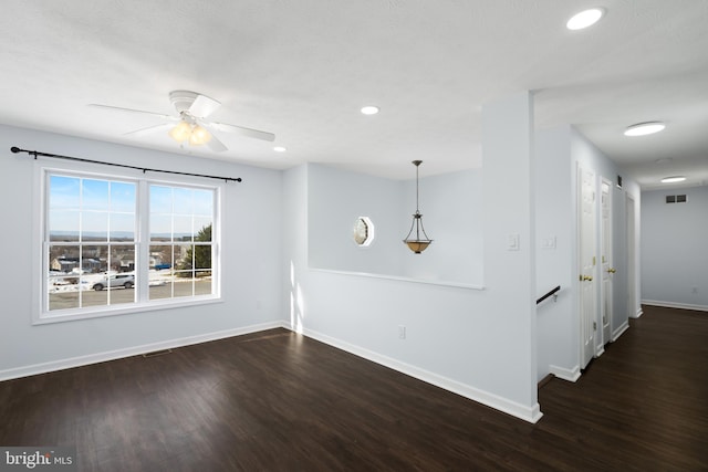 empty room featuring dark wood-type flooring and ceiling fan