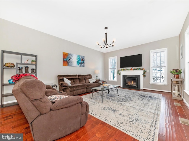 living room with dark wood-type flooring, a notable chandelier, and plenty of natural light