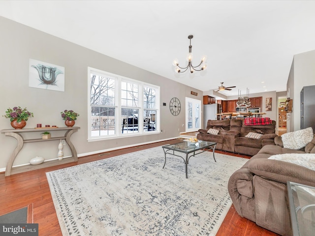 living room featuring ceiling fan with notable chandelier and light hardwood / wood-style floors