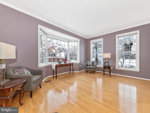 sitting room with light wood-type flooring and ornamental molding