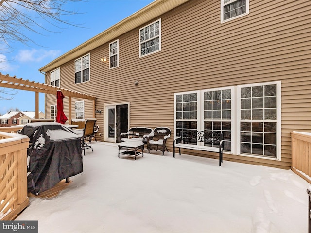 snow covered rear of property with an outdoor living space and a pergola