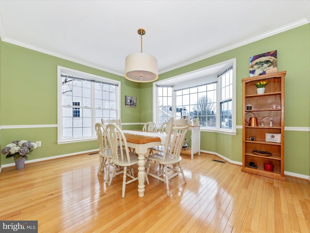 dining area featuring ornamental molding and light hardwood / wood-style floors