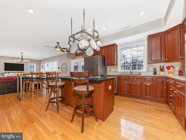 kitchen with a center island, light hardwood / wood-style floors, sink, a breakfast bar, and stainless steel fridge