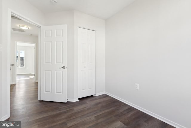 unfurnished bedroom with dark hardwood / wood-style flooring and a closet