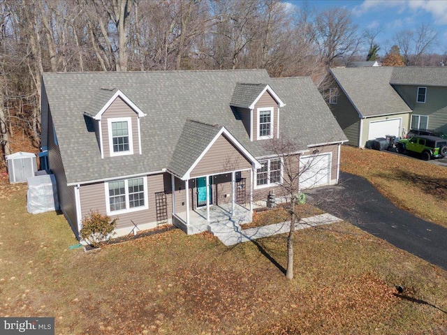 cape cod home featuring a porch, a garage, and a front yard