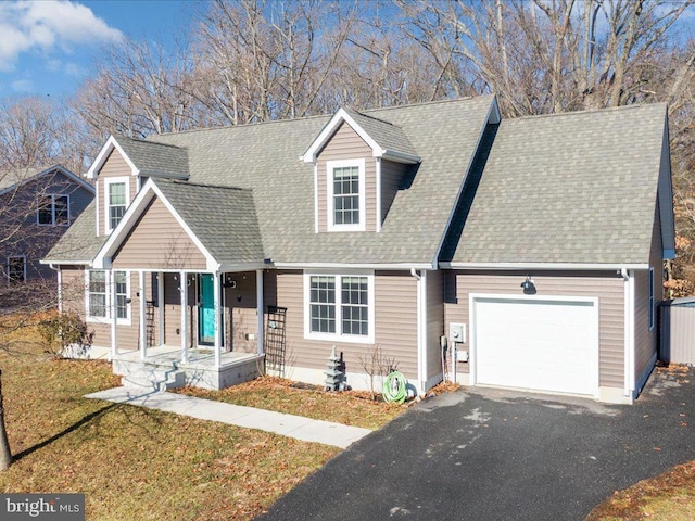 cape cod house featuring a garage, covered porch, and a front yard