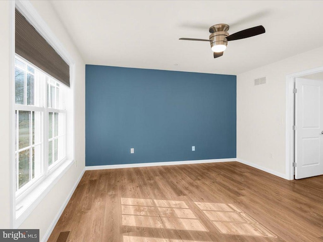 spare room featuring wood-type flooring, plenty of natural light, and ceiling fan