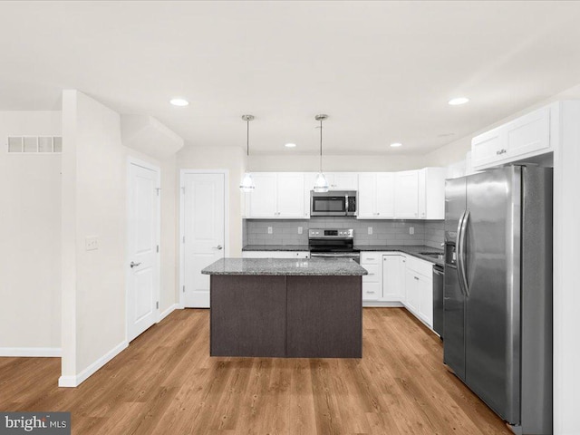 kitchen featuring a center island, hardwood / wood-style flooring, appliances with stainless steel finishes, pendant lighting, and white cabinets