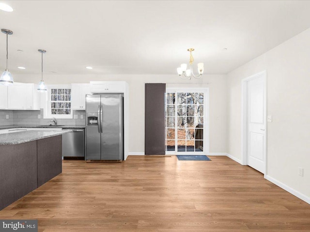 kitchen featuring white cabinetry, backsplash, stainless steel appliances, dark brown cabinetry, and decorative light fixtures