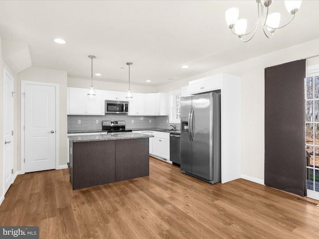 kitchen featuring pendant lighting, appliances with stainless steel finishes, a kitchen island, and white cabinets