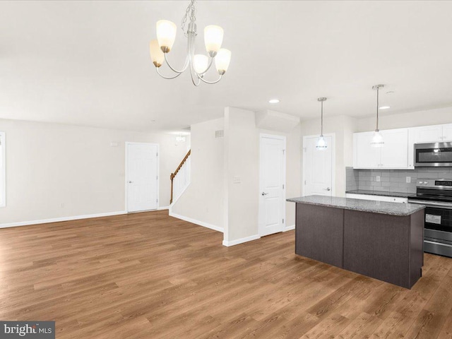 kitchen with white cabinetry, hanging light fixtures, backsplash, stainless steel appliances, and a kitchen island