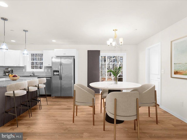 dining area with sink, light hardwood / wood-style floors, and a notable chandelier