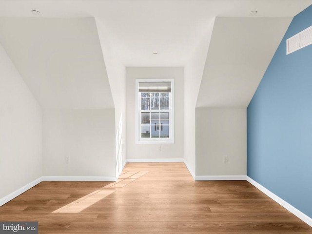 additional living space featuring lofted ceiling and light hardwood / wood-style flooring