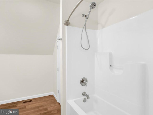 bathroom featuring lofted ceiling, hardwood / wood-style floors, and bathtub / shower combination