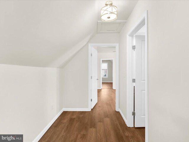 corridor with vaulted ceiling and dark hardwood / wood-style floors