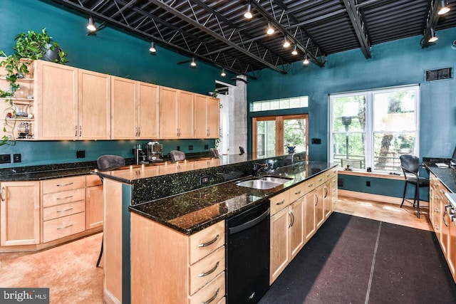 kitchen with black dishwasher, visible vents, a towering ceiling, light brown cabinetry, and a sink