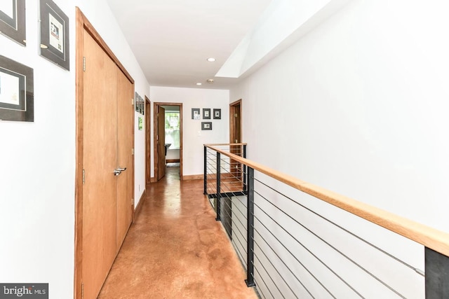 hallway with finished concrete flooring, an upstairs landing, and recessed lighting