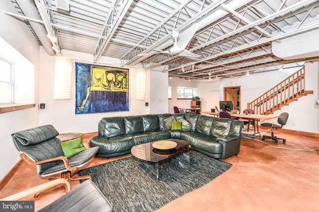 living room featuring stairway, baseboards, and concrete flooring