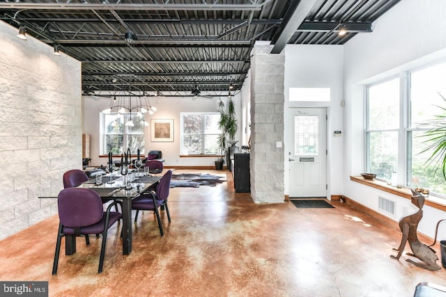 dining space with finished concrete flooring, baseboards, a high ceiling, and visible vents