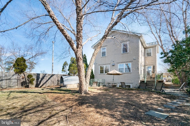 rear view of house featuring fence, an outdoor structure, and a storage shed