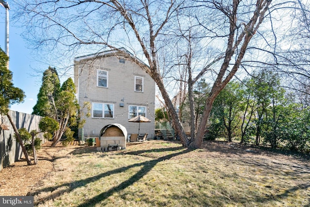 rear view of property featuring stairway, fence, and a lawn