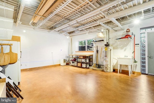 miscellaneous room with baseboards, water heater, finished concrete floors, and a sink