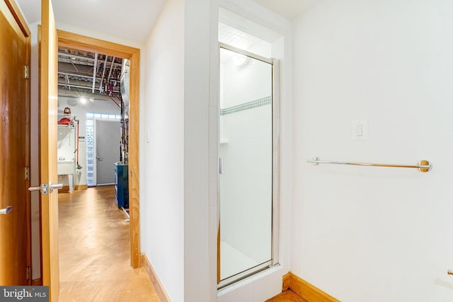 bathroom featuring concrete flooring, a sink, a shower stall, and baseboards