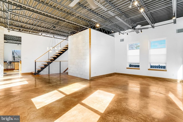 interior space featuring concrete flooring, a high ceiling, visible vents, and baseboards