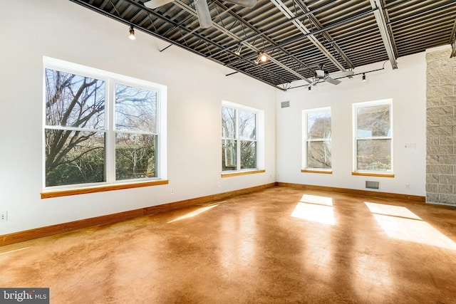 unfurnished room featuring track lighting, visible vents, concrete floors, and baseboards