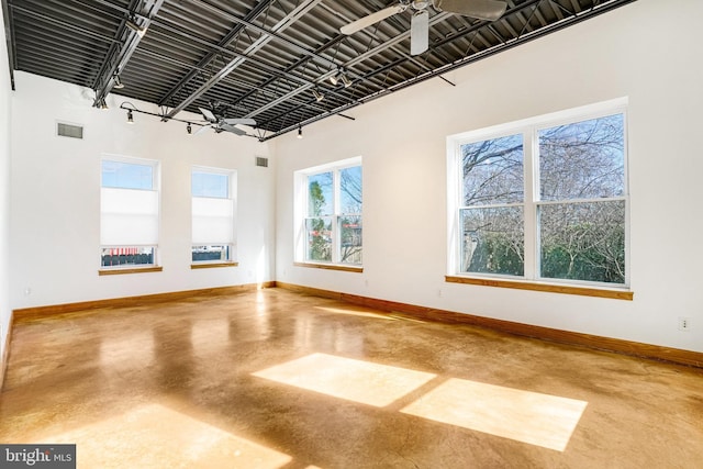 empty room with ceiling fan, concrete floors, visible vents, and baseboards