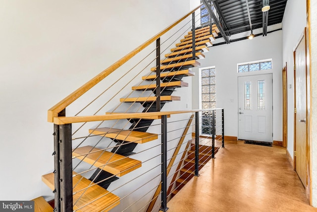 stairs featuring a towering ceiling and concrete floors